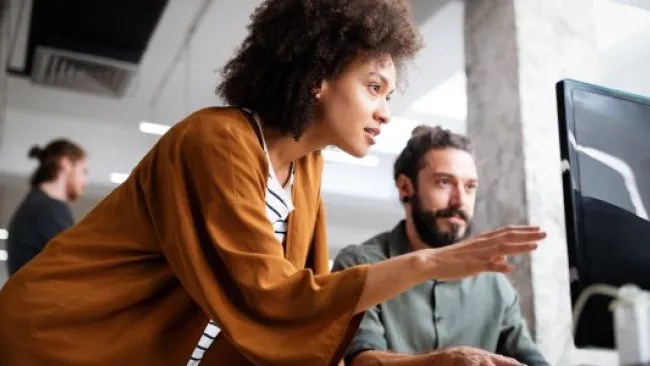 A woman discussing what's on the screen to her colleague
