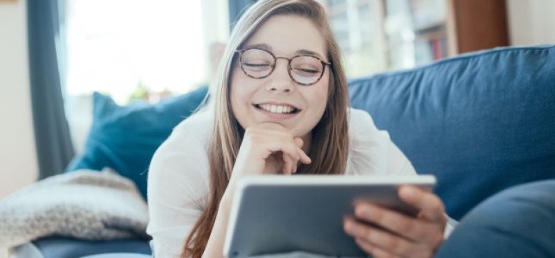 A woman on the couch looking at her tablet