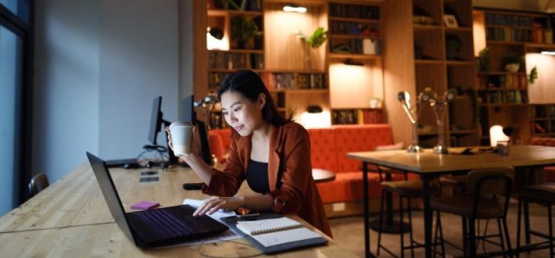A woman working while holding a cup of coffee