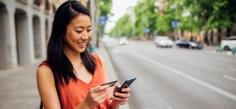 A woman holding her card and phone